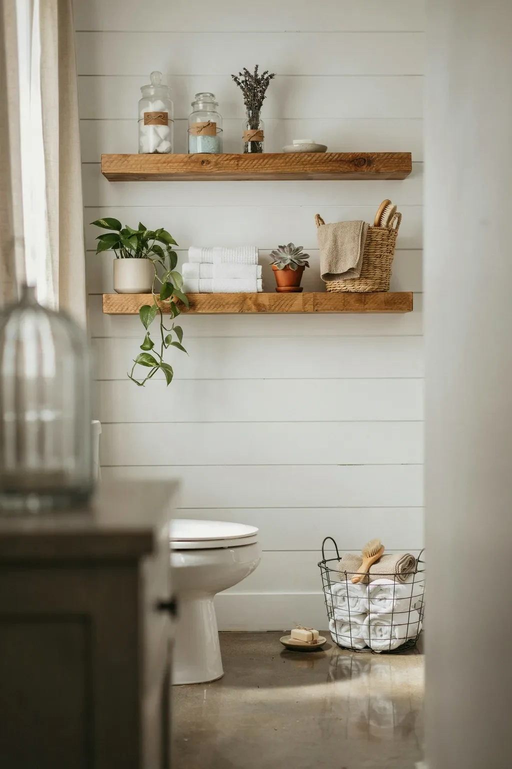 Farmhouse bathroom with styled reclaimed-wood shelves above the toilet