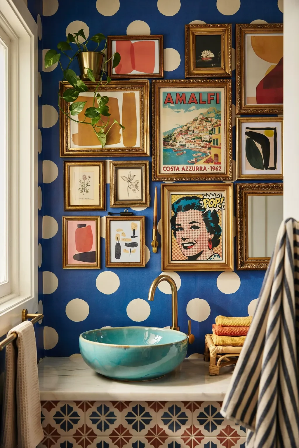 Funky bathroom with polka-dot wallpaper and a gold-frame gallery wall of colorful art