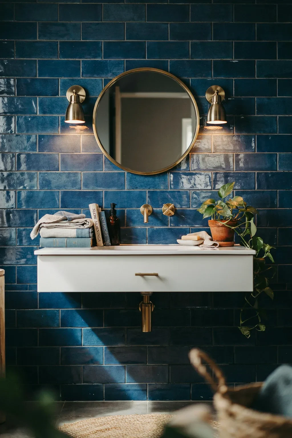 Floating white vanity against a deep blue subway tile wall