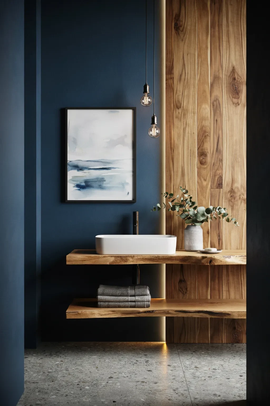 Moody inky blue bathroom with a warm wood plank wall and framed seascape art