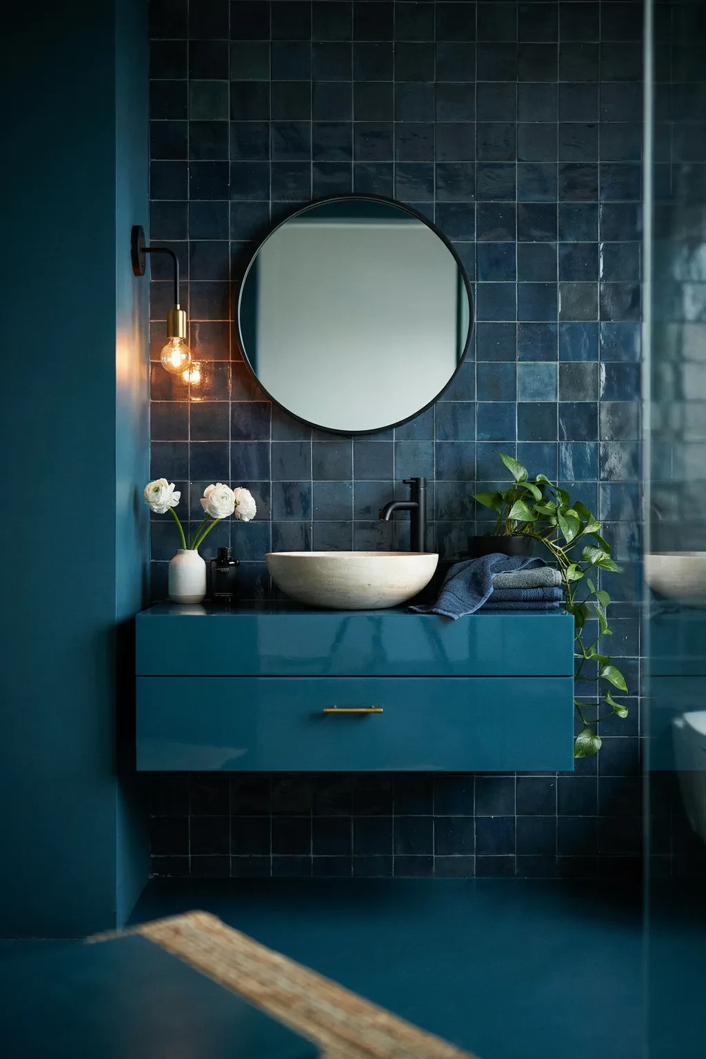 Moody blue bathroom with a glossy teal vanity and matte black fixtures
