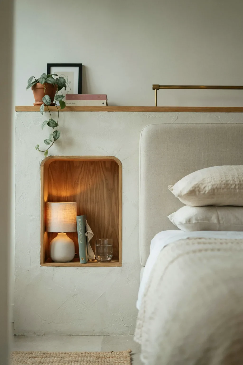 Built-in wood bedside niche storage in a small bedroom