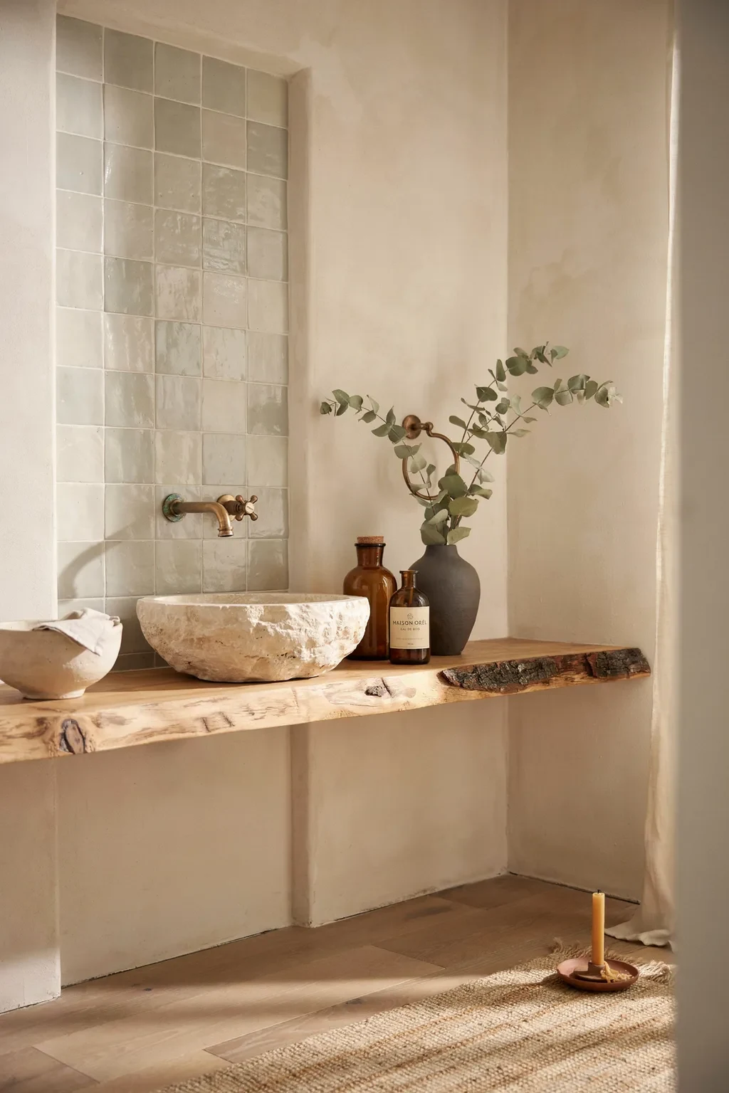 Wabi sabi bathroom showcasing natural materials - zellige tile, live-edge oak, travertine stone basin and aged brass